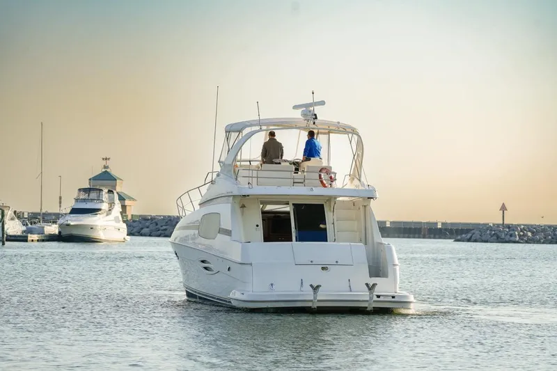  Yacht Photos Pics 2003 Silverton 410 Sport Bridge yacht cruising in a serene marina at sunset.