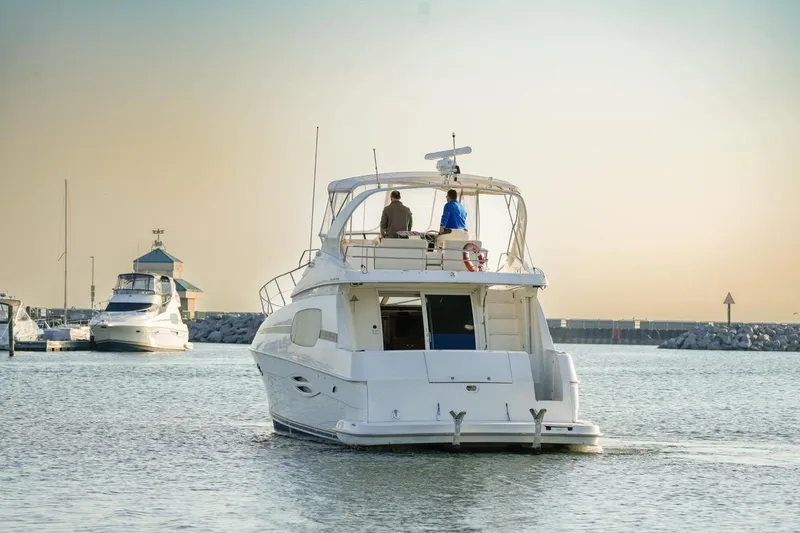  Yacht Photos Pics 2003 Silverton 410 Sport Bridge yacht cruising in a serene marina at sunset.