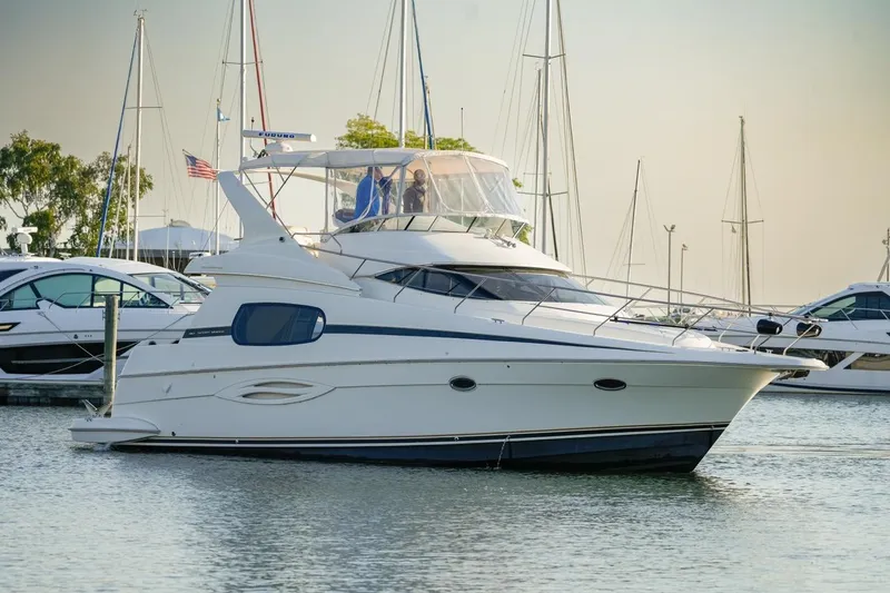  Yacht Photos Pics 2003 Silverton 410 Sport Bridge yacht docked in a marina, surrounded by sailboats.
