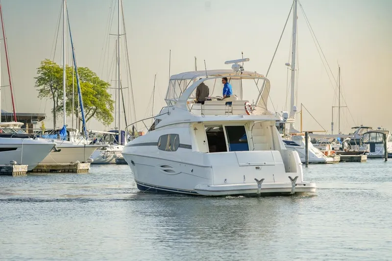  Yacht Photos Pics 2003 Silverton 410 Sport Bridge yacht in a marina, surrounded by sailboats.