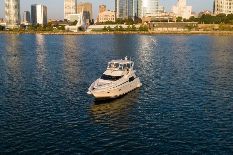  Yacht Photos Pics 2003 Silverton 410 Sport Bridge yacht on water with city skyline backdrop.
