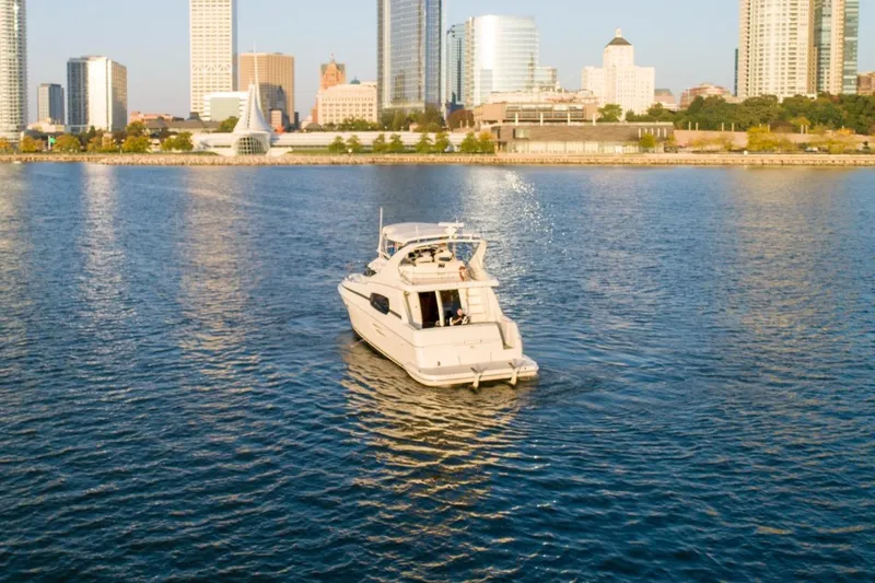  Yacht Photos Pics 2003 Silverton 410 Sport Bridge yacht cruising near city skyline on a sunny day.
