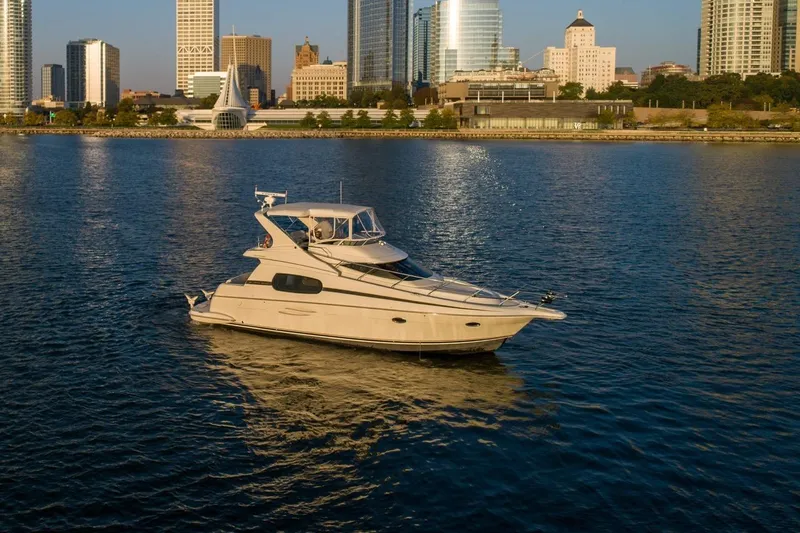  Yacht Photos Pics 2003 Silverton 410 Sport Bridge yacht on calm water with city skyline backdrop.