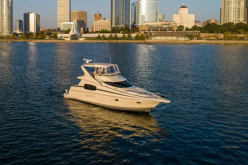  Yacht Photos Pics 2003 Silverton 410 Sport Bridge yacht on calm water with city skyline backdrop.