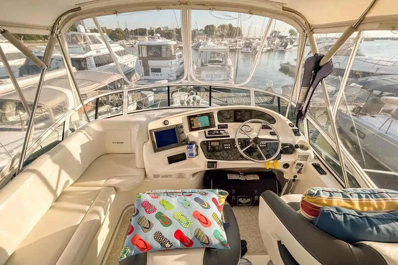  Yacht Photos Pics 2003 Silverton 410 Sport Bridge yacht interior with helm, colorful cushions, and marina view.