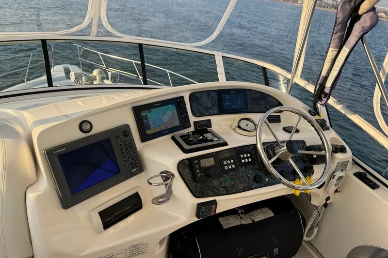  Yacht Photos Pics 2003 Silverton 410 Sport Bridge helm with navigation equipment and steering wheel, overlooking the water.