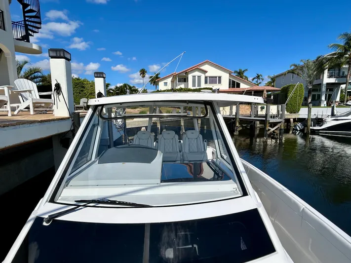 All Gas No Brakes Yacht Photos Pics 2020 Regal 33 SAV boat docked near waterfront homes under a clear blue sky.