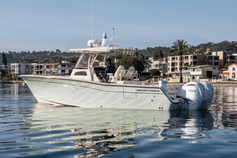  Yacht Photos Pics 2022 Grady-White Canyon 306 boat on calm water near modern waterfront homes.