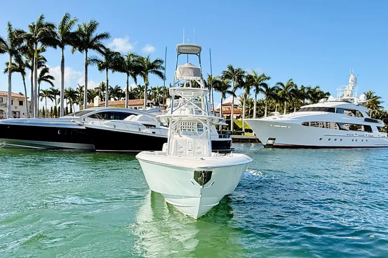 Scott Free Yacht Photos Pics 2024 Contender 44 ST boat docked near luxury yachts and palm trees.
