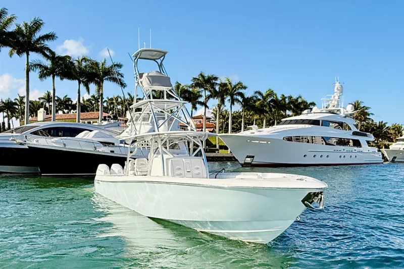 Scott Free Yacht Photos Pics 2024 Contender 44 ST boat docked in a marina with luxury yachts and palm trees.