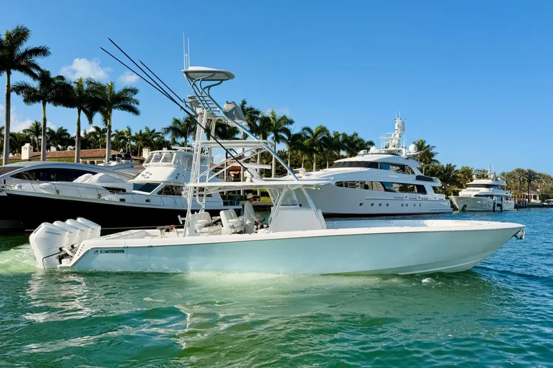 Scott Free Yacht Photos Pics 2024 Contender 44 ST boat on water, surrounded by yachts and palm trees.