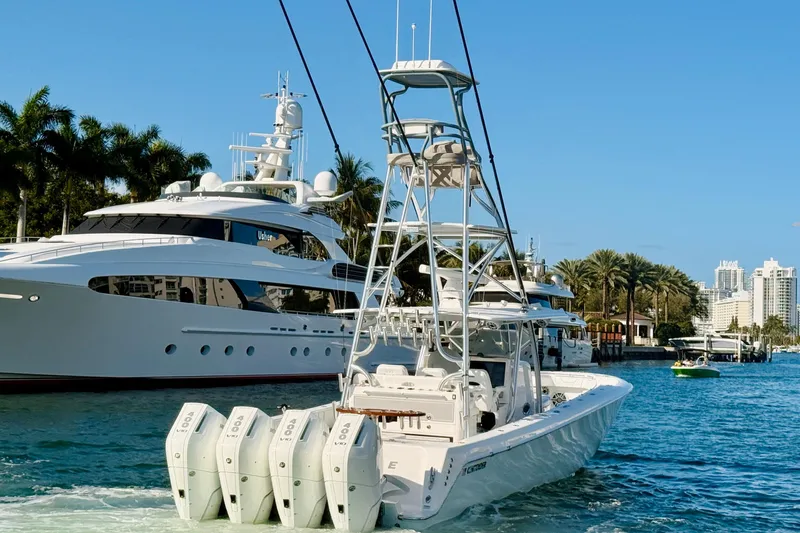 Scott Free Yacht Photos Pics 2024 Contender 44 ST boat with four engines cruising near luxury yachts and palm trees.