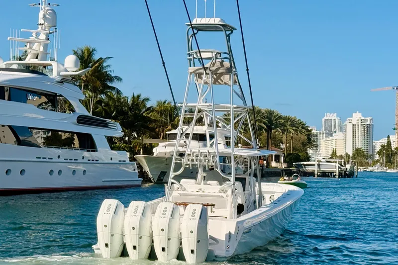 Scott Free Yacht Photos Pics 2024 Contender 44 ST boat with quad engines cruising in a marina, surrounded by yachts and palm trees.