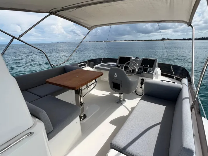 Sarandipity Yacht Photos Pics 2024 Beneteau Swift Trawler 41 Flybridge with seating, table, and helm, overlooking the ocean.