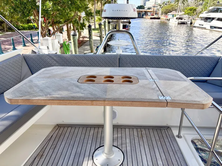 Micky's Dream Yacht Photos Pics Flybridge table on 2020 Greenline 45 Fly yacht, overlooking marina with lush greenery.