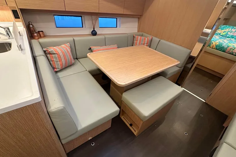 Dream Time Yacht Photos Pics Modern Bavaria C45 yacht interior with cozy dining area, featuring cushioned seating and wooden table.
