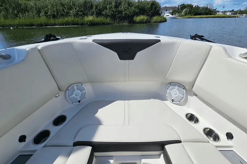  Yacht Photos Pics 2023 Sailfish 276 DC boat interior with cushioned seating and speakers, docked by a scenic waterway.