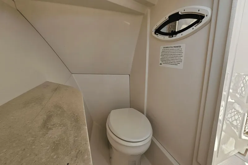  Yacht Photos Pics 2023 Sailfish 276 DC boat bathroom interior with toilet and small window.