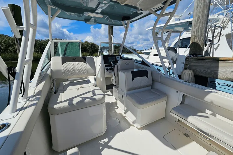  Yacht Photos Pics 2023 Sailfish 276 DC boat interior with seating and helm, docked under blue sky.
