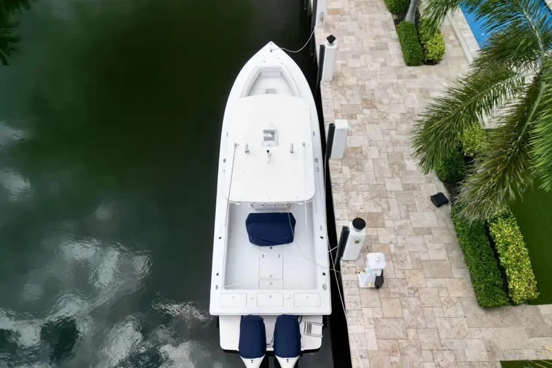  Yacht Photos Pics Aerial view of a 2007 Jupiter 31 boat docked beside a stone patio with lush greenery.