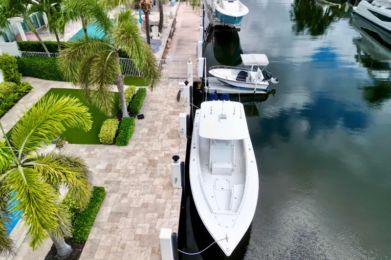  Yacht Photos Pics Aerial view of a 2007 Jupiter 31 boat docked by a lush, tropical waterfront.