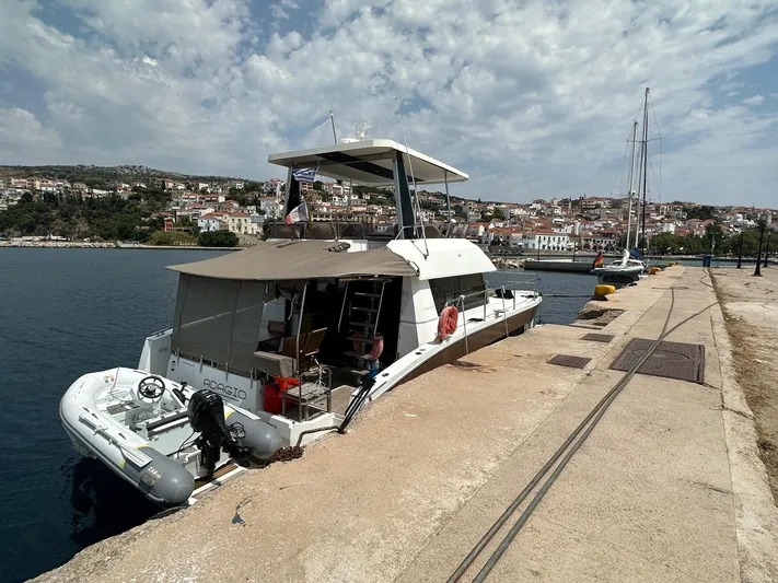 Yacht Photos Pics 2016 Fountaine Pajot MY 37 yacht docked at a scenic harbor under a partly cloudy sky.