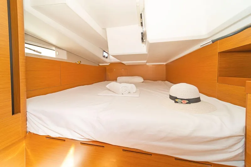 Yacht Photos Pics Cozy cabin interior of 2020 Jeanneau Sun Odyssey 490 with bed and hat.