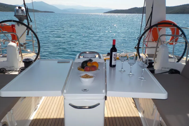  Yacht Photos Pics Jeanneau Sun Odyssey 490 yacht deck with wine, fruit, and glasses, 2020 model.