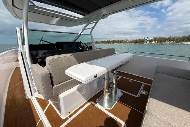  Yacht Photos Pics 2024 Axopar 37 Sun-Top boat interior with seating and table, overlooking serene waters.
