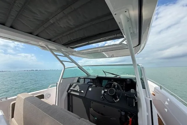  Yacht Photos Pics 2024 Axopar 37 Sun-Top boat interior with ocean view, featuring modern helm and seating.