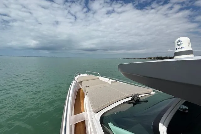  Yacht Photos Pics 2024 Axopar 37 Sun-Top cruising on calm waters under a partly cloudy sky.