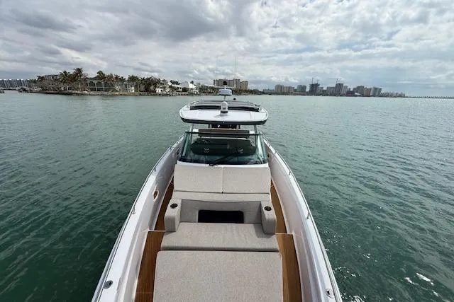  Yacht Photos Pics 2024 Axopar 37 Sun-Top boat cruising on calm waters under a cloudy sky.