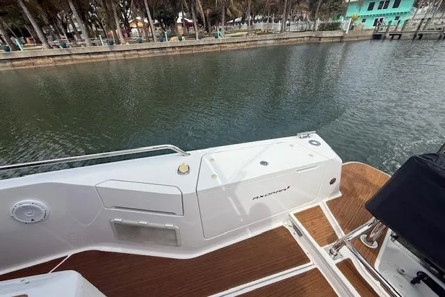  Yacht Photos Pics 2024 Axopar 37 Sun-Top boat deck with wood finish, docked by calm waters.