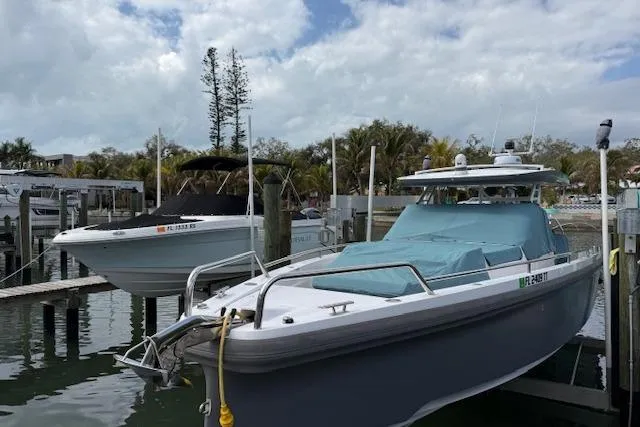  Yacht Photos Pics 2024 Axopar 37 Sun-Top boat docked in a marina under cloudy skies.