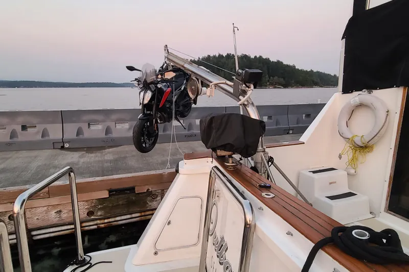 Outbound Yacht Photos Pics 1993 Symbol 55 Yachtfisher with motorcycle on deck, docked by serene waters.