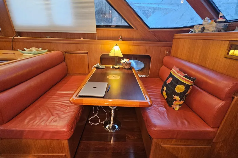 Outbound Yacht Photos Pics Cozy dining area on 1993 Symbol 55 Yachtfisher with red leather seating and wooden table.