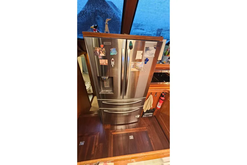 Outbound Yacht Photos Pics Stainless steel refrigerator in a 1993 Symbol 55 Yachtfisher kitchen, with magnets and decor.