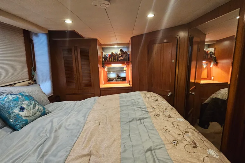 Outbound Yacht Photos Pics Luxurious bedroom interior of a 1993 Symbol 55 Yachtfisher, featuring elegant wood paneling.