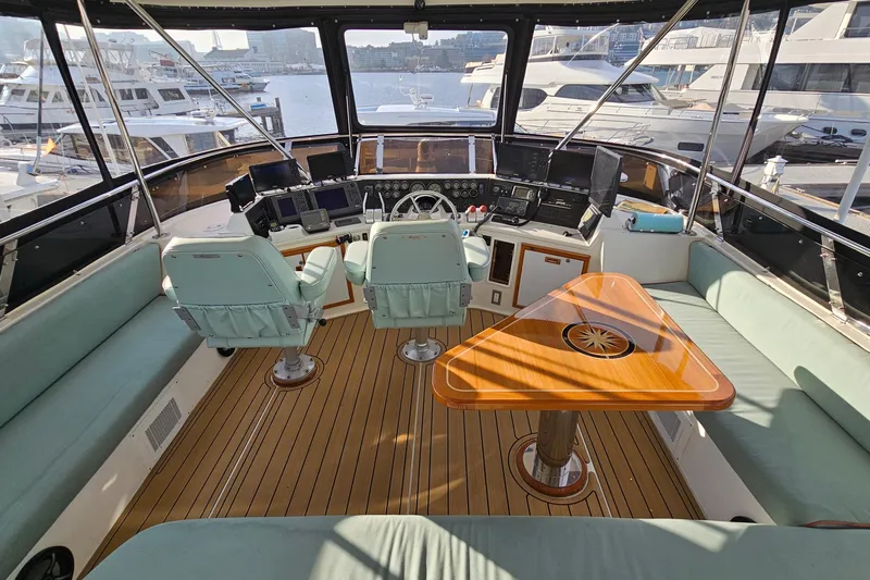 Outbound Yacht Photos Pics Luxurious 1993 Symbol 55 Yachtfisher cockpit with helm, seating, and wooden table, docked at marina.