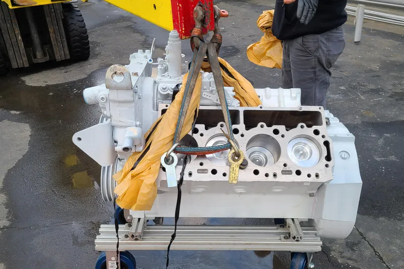 Outbound Yacht Photos Pics Engine block being hoisted, likely for a 1993 Symbol 55 Yachtfisher, on a wet surface.