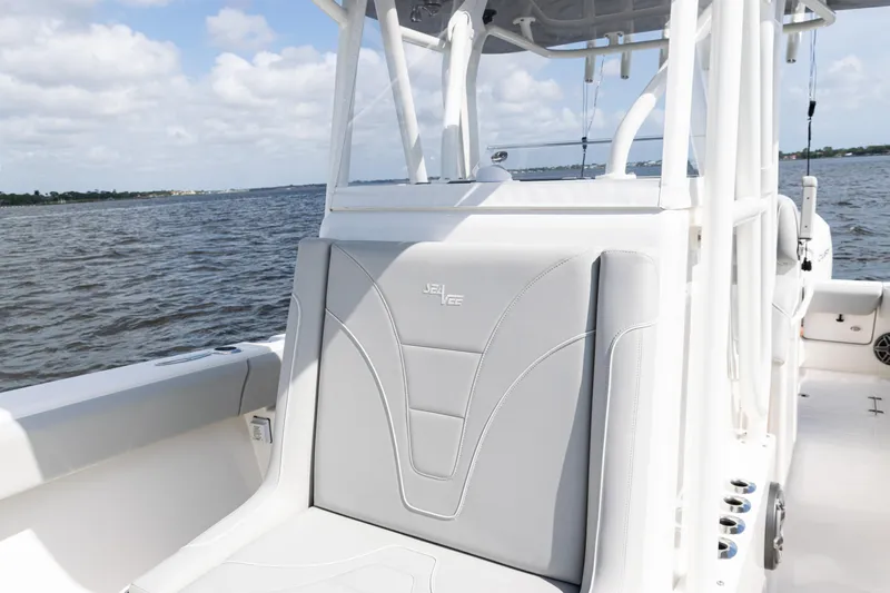  Yacht Photos Pics 2024 SeaVee 290B boat with sleek seating, cruising on a calm waterway under a partly cloudy sky.