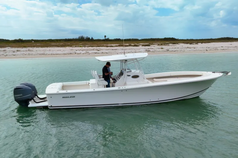 Redemption Yacht Photos Pics 2012 Regulator 34SS boat on calm water near sandy shore, under a cloudy sky.