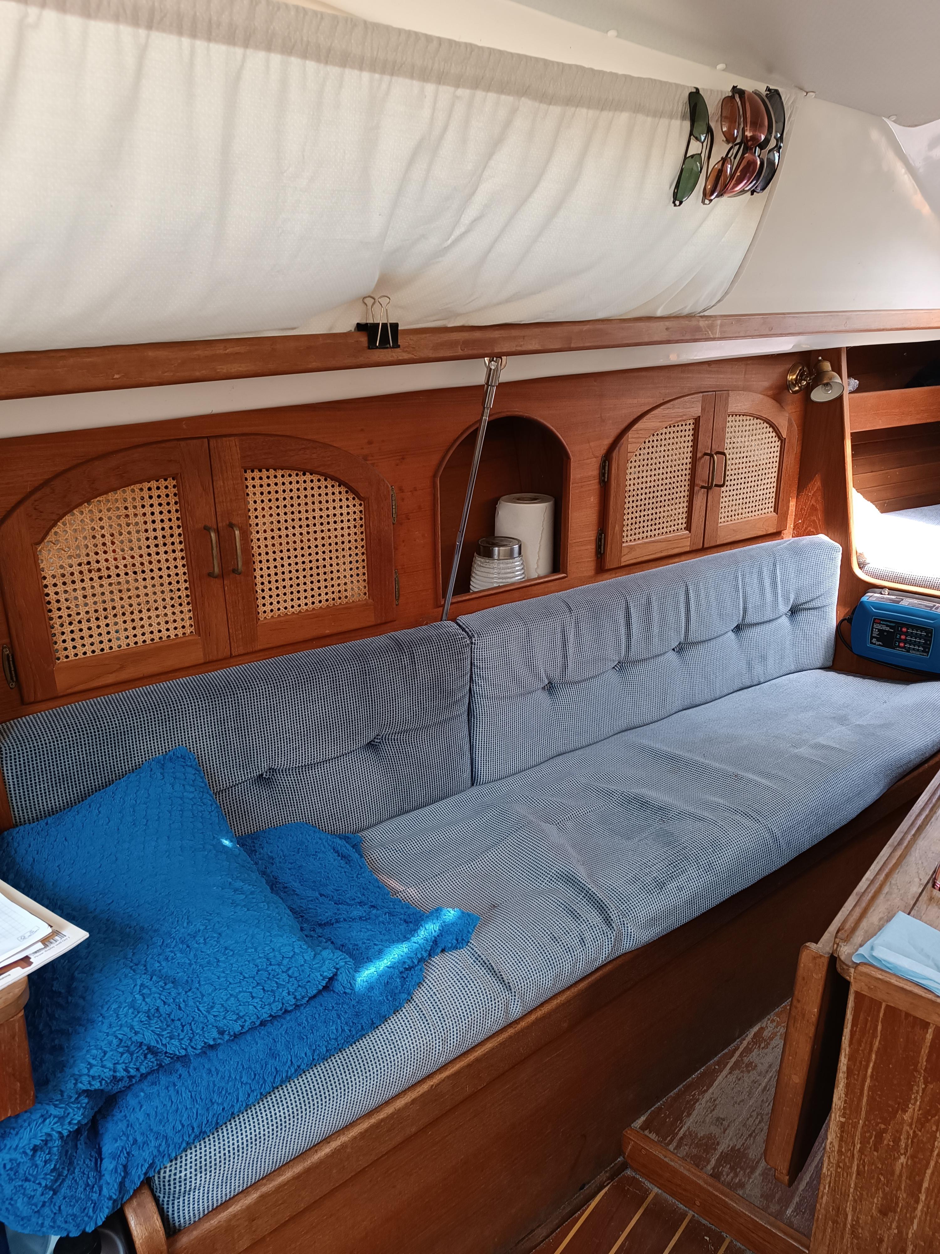 Interior of 1988 Aloha 30 sailboat with cozy seating and wooden cabinetry.