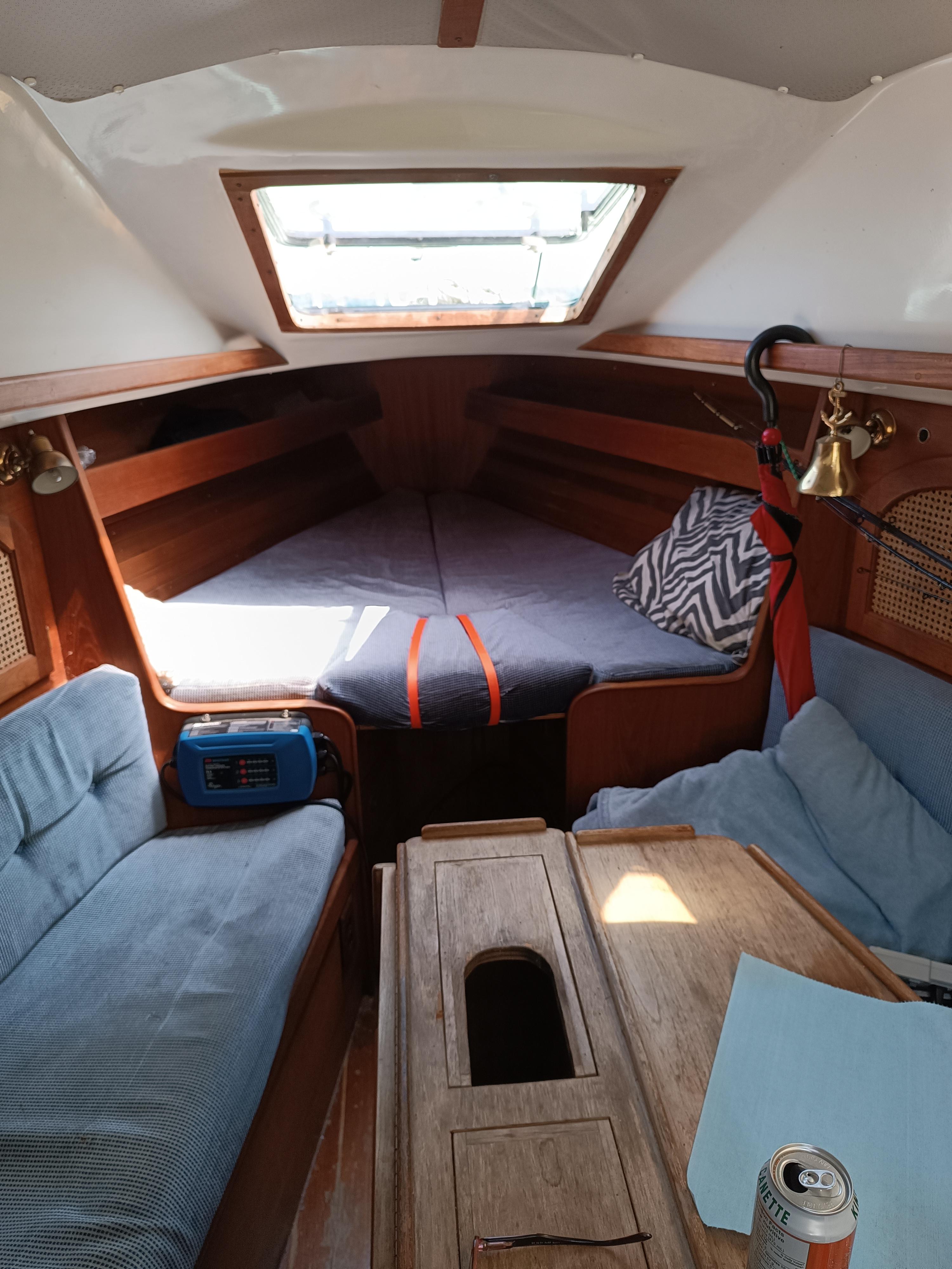 Interior of 1988 Aloha 30 sailboat with cozy seating and wooden table.