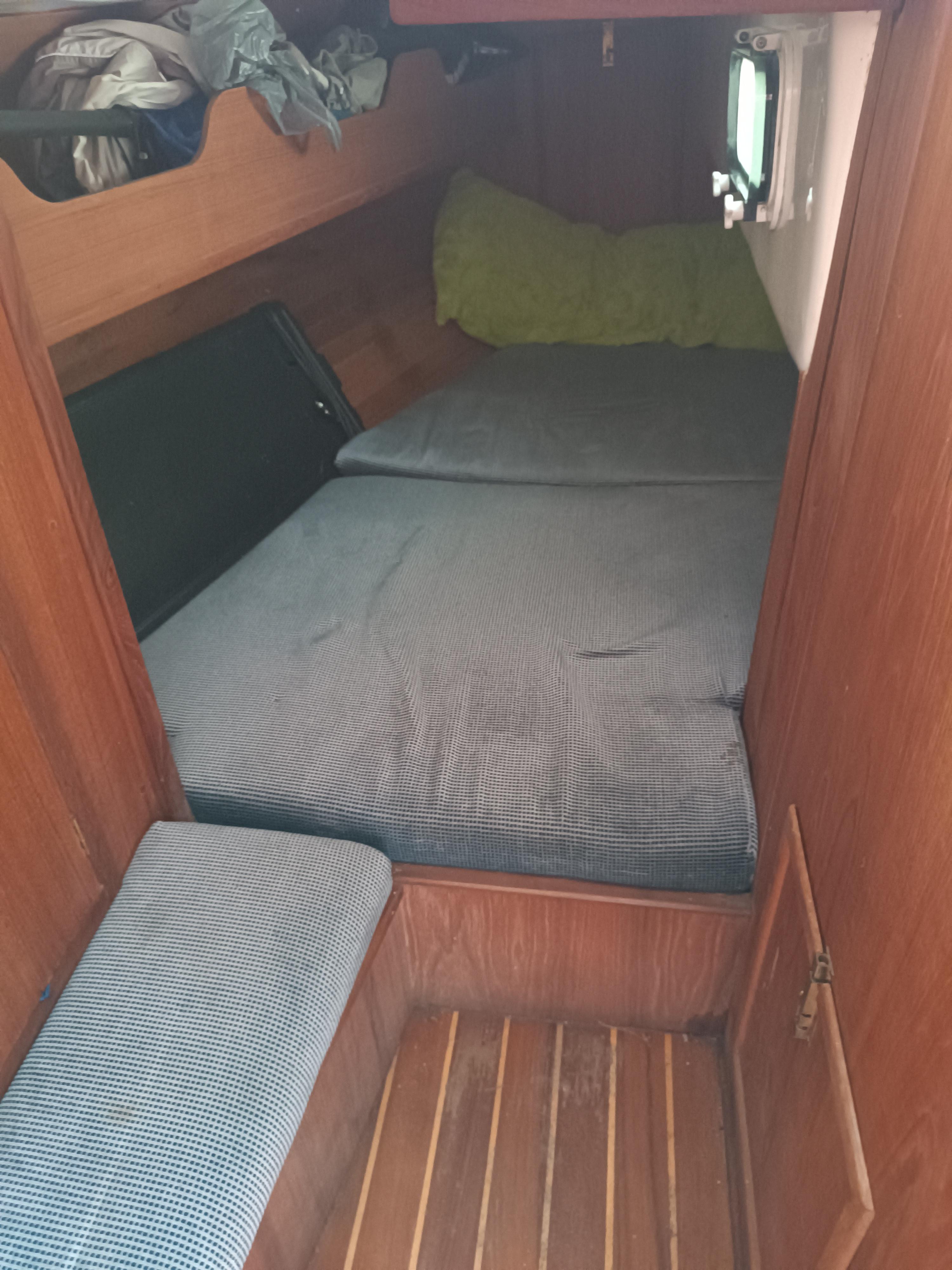 Cozy cabin interior of 1988 Aloha 30 sailboat with wooden finish and bedding.