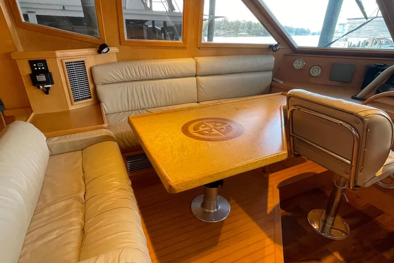 Aventis Yacht Photos Pics Interior of 1999 McKinna 57 Pilothouse with wooden table and leather seating.