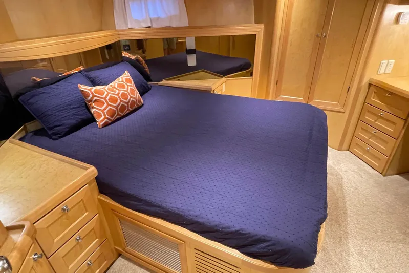 Aventis Yacht Photos Pics Luxurious bedroom in 1999 McKinna 57 Pilothouse yacht with navy bedding and wooden cabinetry.