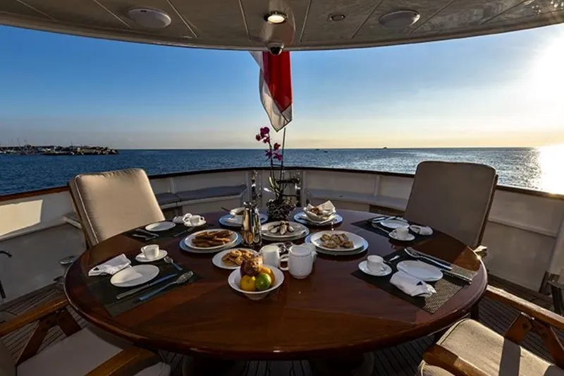 Don Ciro Yacht Photos Pics Luxury dining setup on Benetti Sail Division 105 yacht, 2002, with ocean view at sunset.