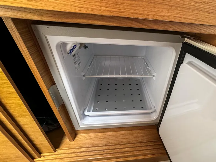 Yacht Photos Pics Open mini fridge inside 2024 De Antonio Yachts D28 Cruiser, featuring wooden cabinetry.