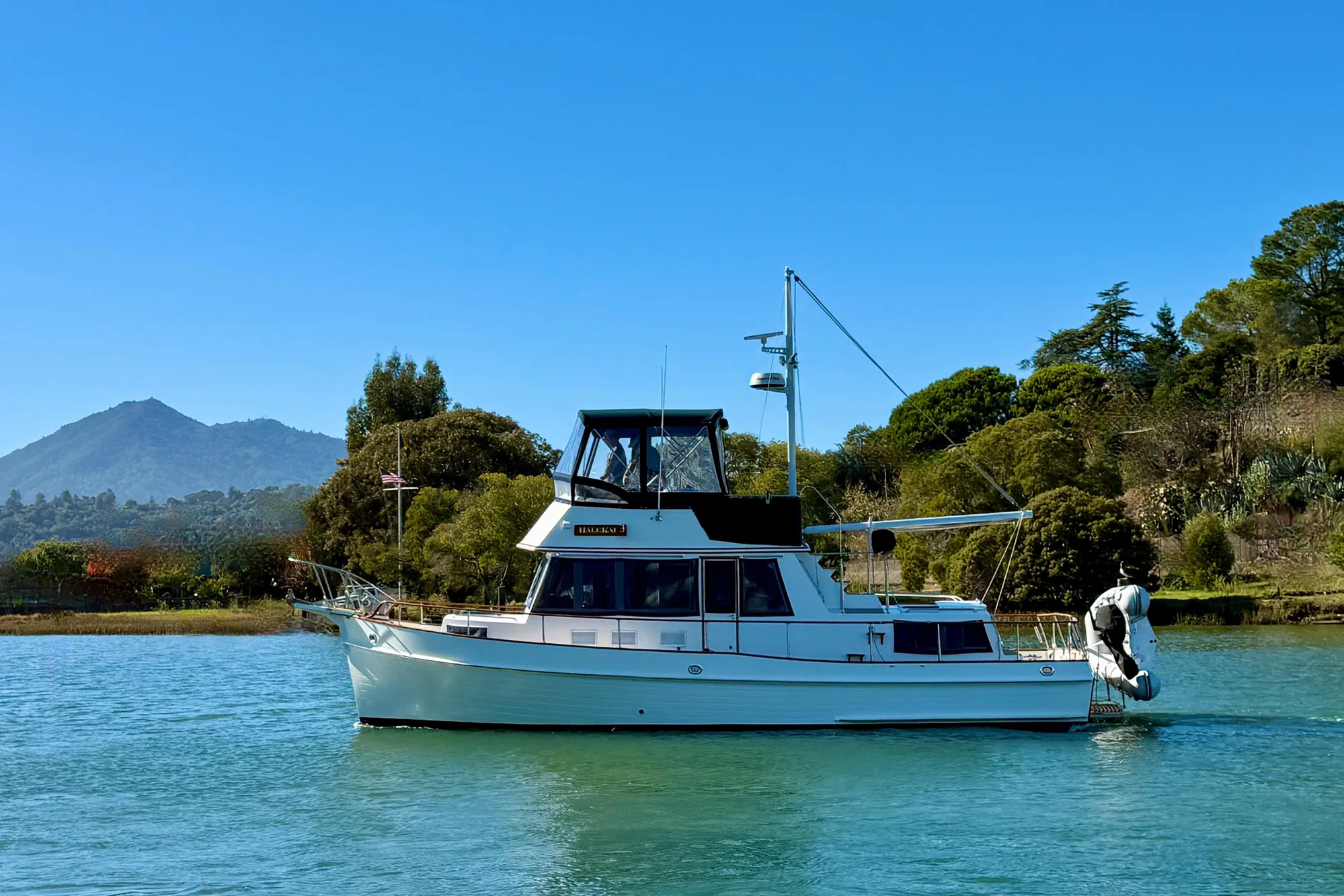 1997 Grand Banks Classic yacht on serene water with scenic mountain backdrop.